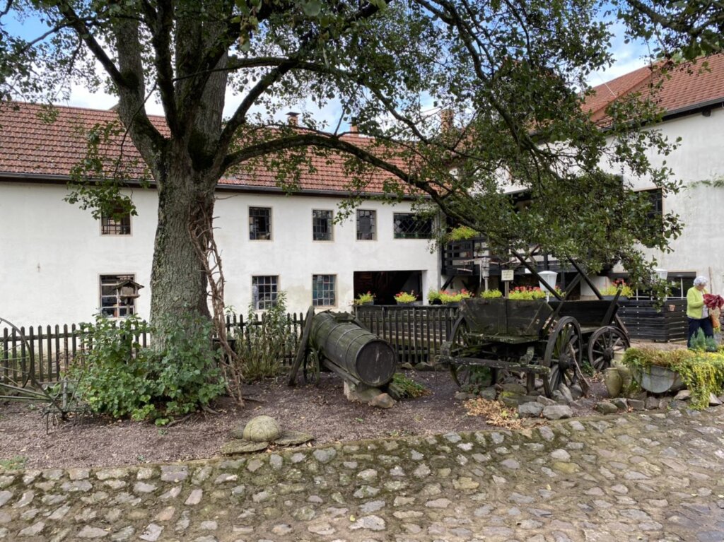 Mühlenhof der Bettinger Mühle mit alter Linde und historischem Leiterwagen